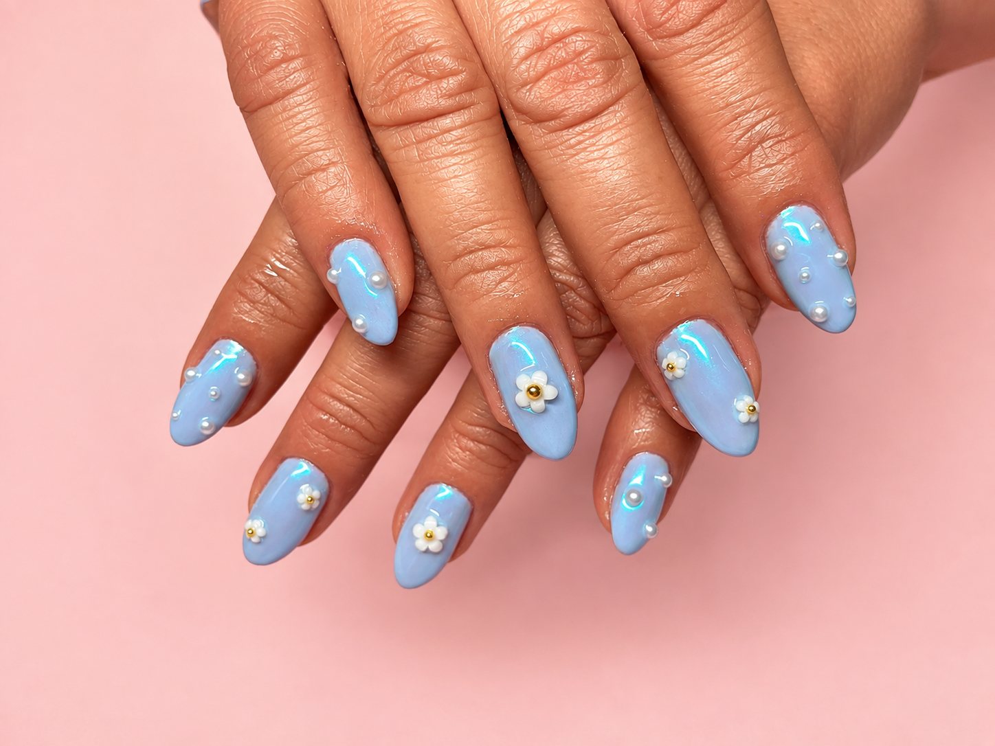 Almond nails in iridescent baby blue with white daisy charms and pearl studs