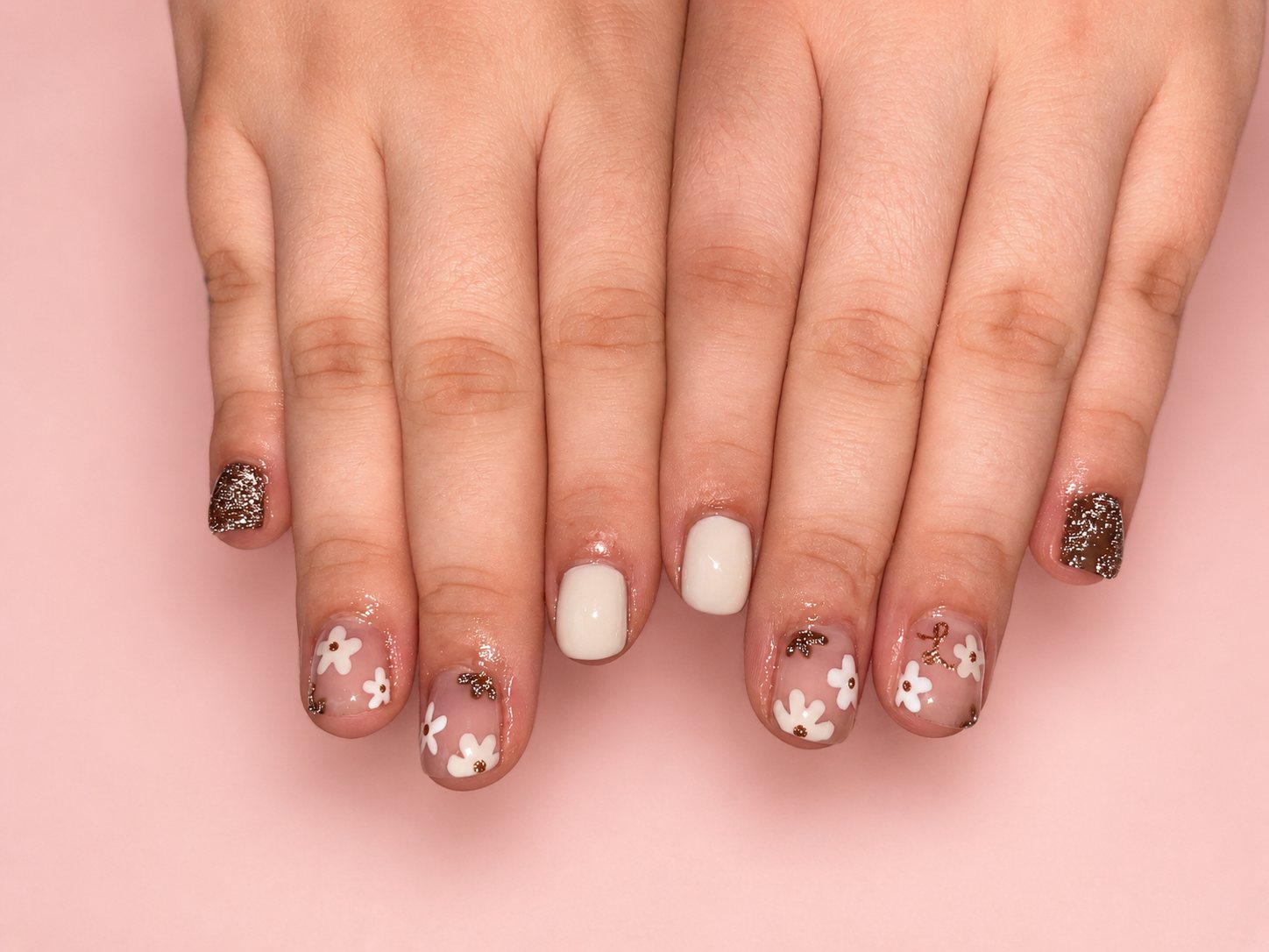 Short round nails in cream with white daisies and bronze glitter accents