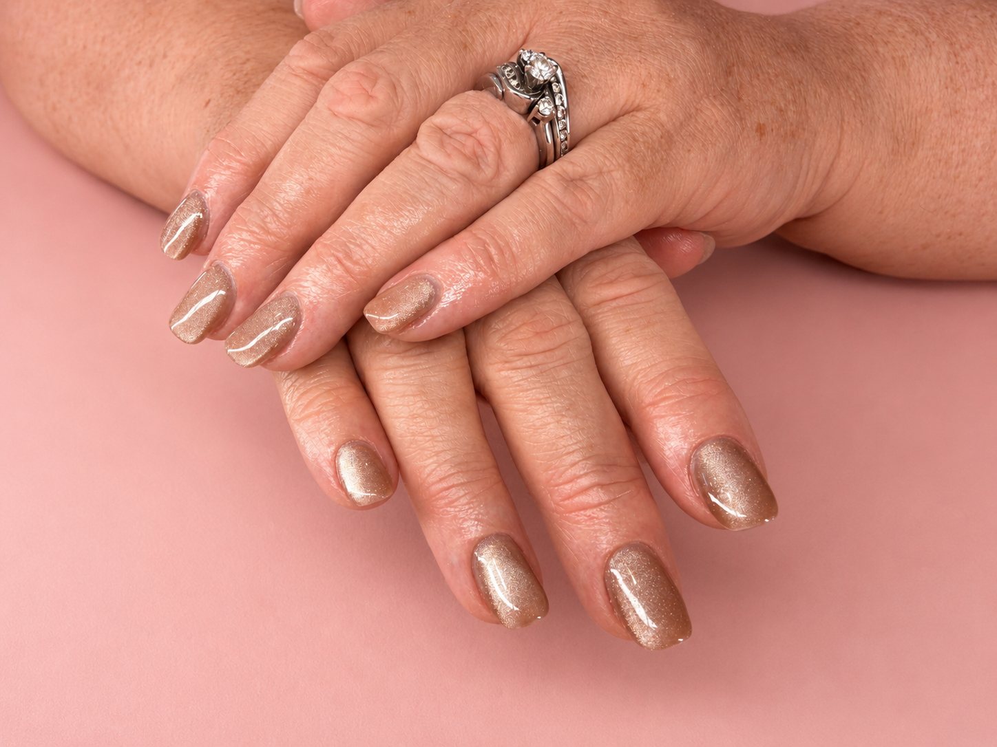 Champagne cat-eye gel manicure shimmering on gently folded hands
