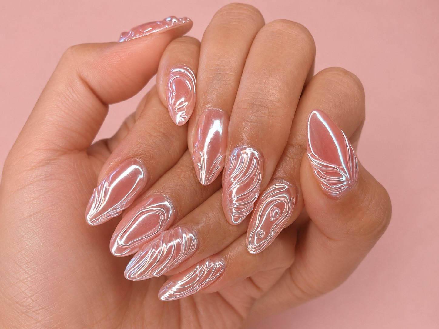 Hand with almond GelX nails in pearl-pink chrome, each nail carrying raised, hand-sculpted swirl lines that catch the light